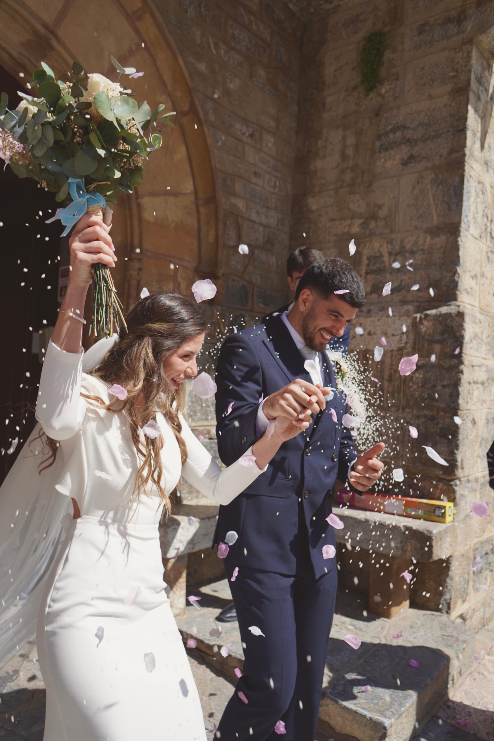 Novios con arroz y pétalos